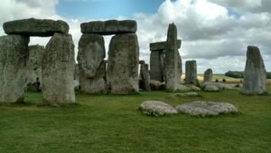 Photo of a subset of Stonehenge, with green grass and some tiny flowers